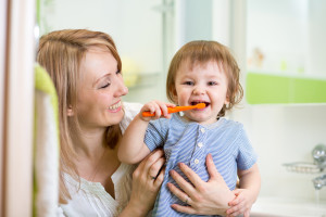 mother teaching son child teeth brushing in bathroom